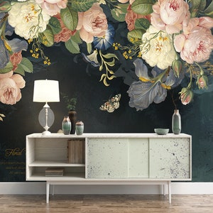 May include: A white dresser with two drawers and two doors. The dresser has a light wood finish and a white top. The dresser is in front of a dark green wall with a floral mural featuring pink, white, and purple flowers.