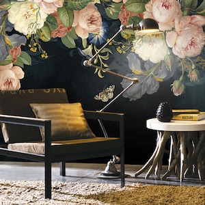 May include: A black armchair with a brown cushion and a throw pillow sits in front of a dark floral wallpaper with a butterfly and a lamp. A small wooden table with a white top and a black decorative object sits next to the chair. The table has a book titled "Jazzlife" on top.