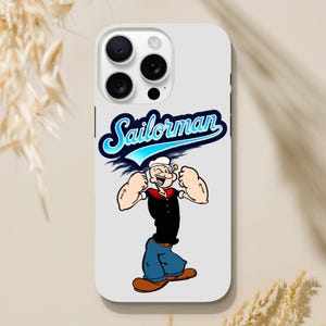Può includere: Custodia bianca per iPhone con un'immagine di cartone animato di Popeye, un marinaio con un colletto blu e un cappello rosso, che flette i muscoli. Il testo "Sailorman" è scritto in lettere blu e bianche sopra l'immagine.
