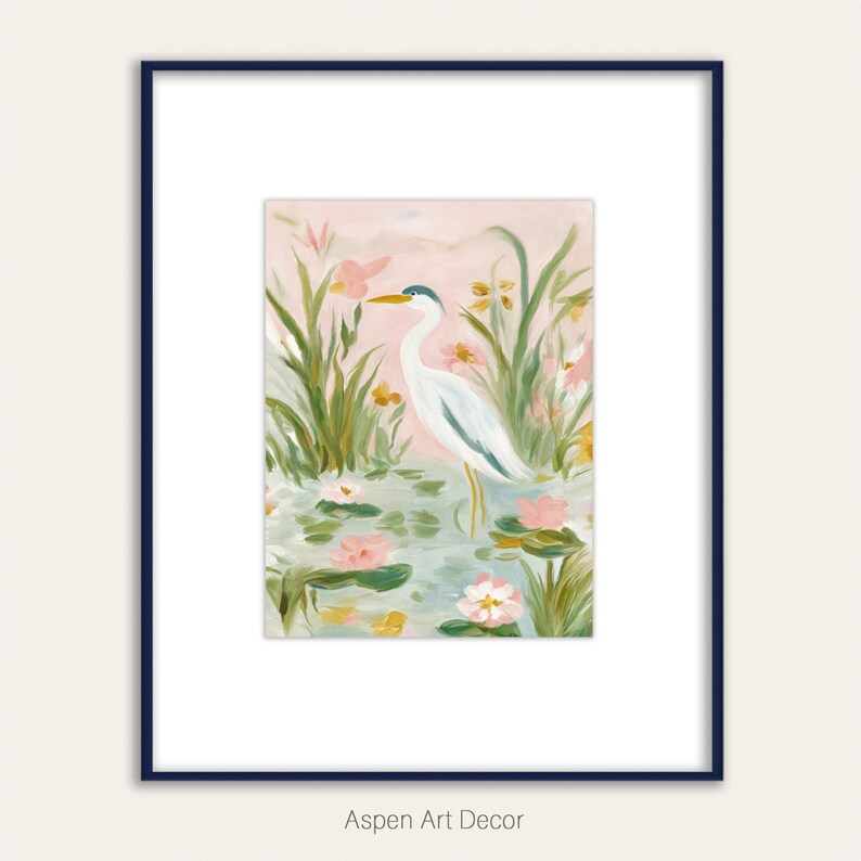May include: A framed art print featuring a serene watercolor painting of a white heron standing in a pond with lily pads and pink flowers. The artwork is set against a soft pink background, framed in a navy blue frame. The text "Aspen Art Decor" is at the bottom.