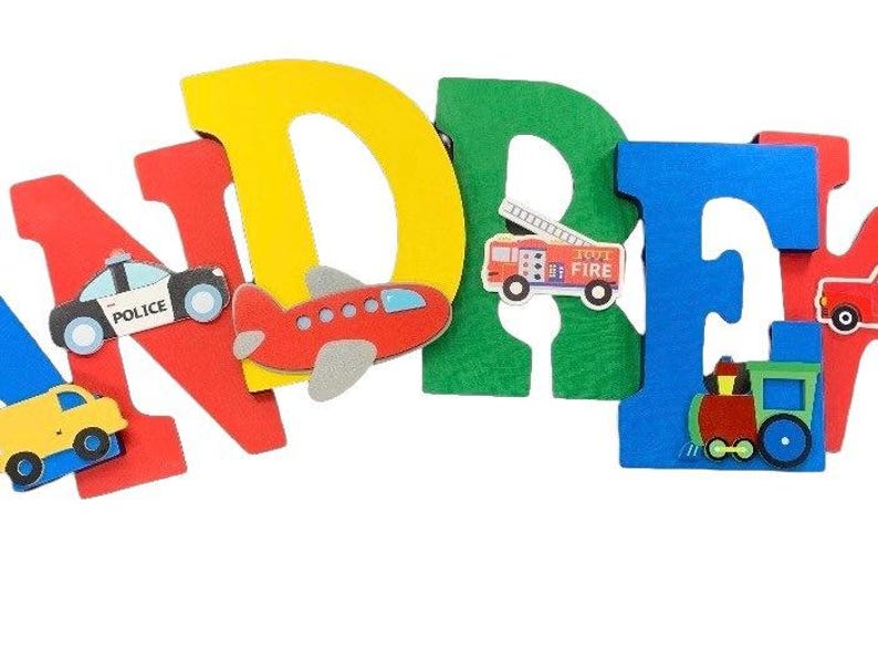 Puede incluir: Letras de madera de colores que deletrean un nombre, decoradas con veh&iacute;culos de juguete. Las letras son rojas, amarillas, verdes y azules. Coches de juguete, un coche de polic&iacute;a, un avi&oacute;n, un cami&oacute;n de bomberos y un tren est&aacute;n adjuntos.