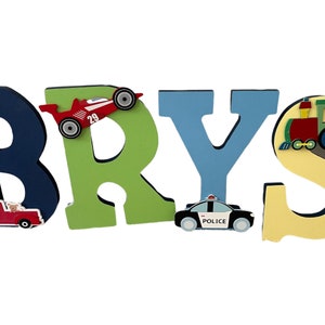 Puede incluir: Letras de madera que deletrean "BRYS" en azul marino, verde y azul claro. Cada letra est&aacute; decorada con un coche de juguete, un coche de carreras, un coche de polic&iacute;a y un tren. Las letras est&aacute;n dise&ntilde;adas para la habitaci&oacute;n de un ni&ntilde;o.