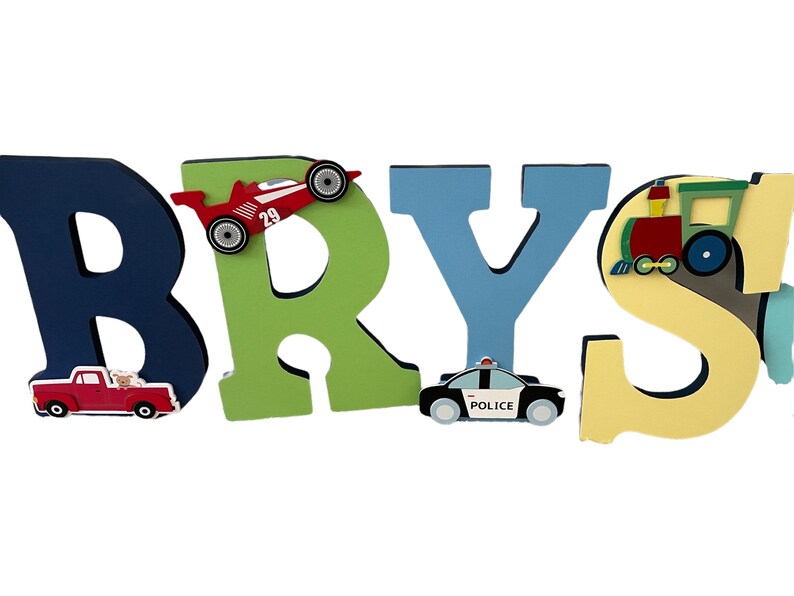 Puede incluir: Letras de madera que deletrean "BRYS" en azul marino, verde y azul claro. Cada letra est&aacute; decorada con un coche de juguete, un coche de carreras, un coche de polic&iacute;a y un tren. Las letras est&aacute;n dise&ntilde;adas para la habitaci&oacute;n de un ni&ntilde;o.