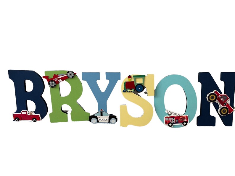 Puede incluir: Letrero de nombre de madera que deletrea "BRYSON" en varios colores. Cada letra est&aacute; decorada con un veh&iacute;culo diferente, incluyendo un coche de carreras, un coche de polic&iacute;a, un tren, un cami&oacute;n de bomberos y un monster truck. Ideal para la habitaci&oacute;n de un ni&ntilde;o.