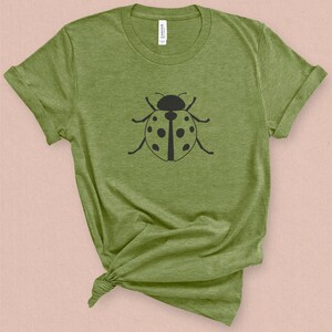 Puede incluir: Una camiseta verde con un gr&aacute;fico de mariquita negra en la parte delantera.