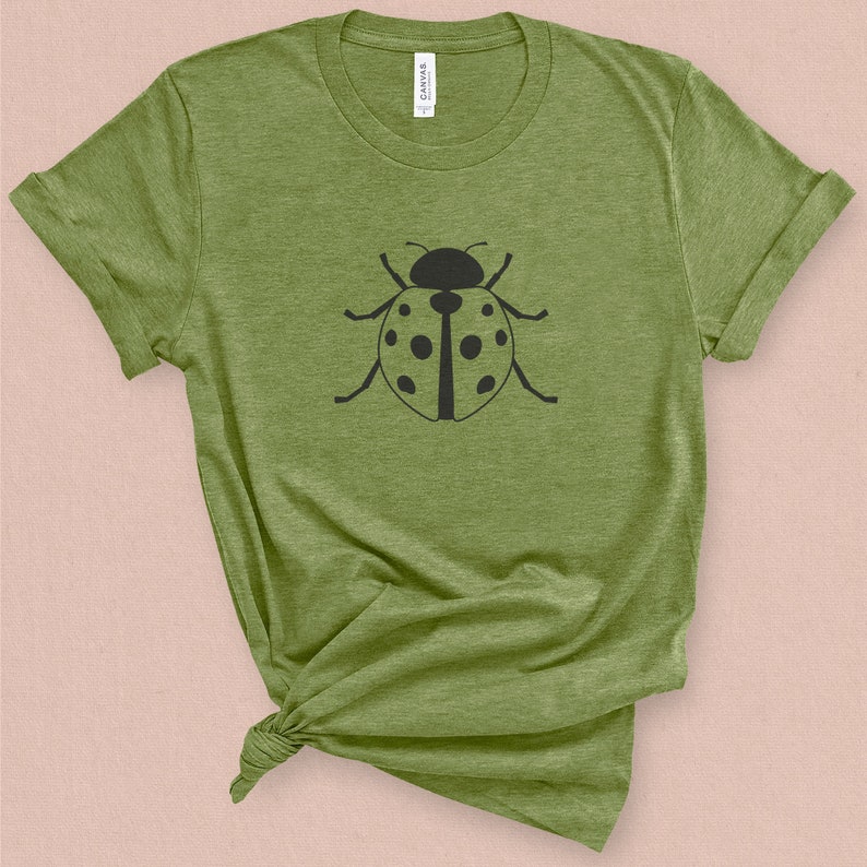 Puede incluir: Una camiseta verde con un gr&aacute;fico de mariquita negra en la parte delantera.