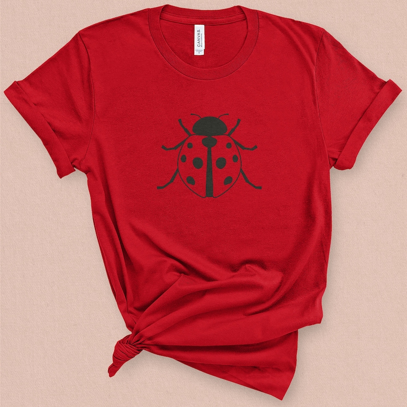 Puede incluir: Camiseta roja con un gr&aacute;fico de mariquita negra.
