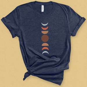 May include: A navy blue t-shirt with a graphic of a vertical row of moons in different phases. The moons are in shades of gray, red, orange, and brown.