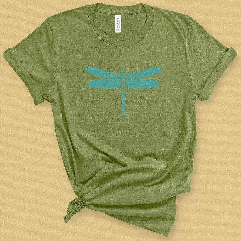 May include: A green t-shirt with a blue dragonfly design. The dragonfly is made up of small circles.
