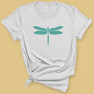 May include: A white t-shirt with a teal dragonfly graphic design.