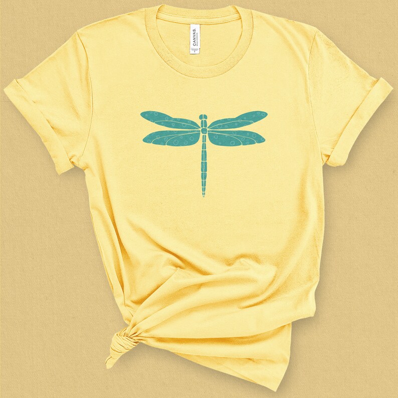 May include: A yellow t-shirt with a teal dragonfly graphic on the front.