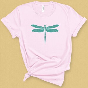 May include: A pink t-shirt with a teal dragonfly graphic design.