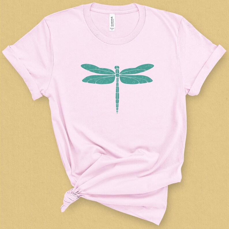May include: A pink t-shirt with a teal dragonfly graphic design.