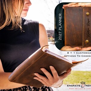 May include: A brown leather planner with a wrap-around closure secured by two brass-colored metal snaps. The cover features the text 2027 PLANNER and a personalized name engraving. The planner is shown open and closed with visible stitching.