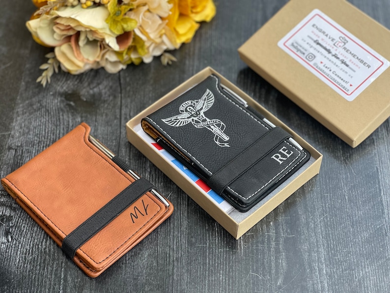 Puede incluir: Dos cubiertas de cuaderno de cuero personalizadas con un portaplumas. Una cubierta es marr&oacute;n con las iniciales "MK" y la otra es negra con un s&iacute;mbolo m&eacute;dico y las iniciales "RE".