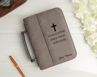 Op de afbeelding: Grijze kunstleren Bijbelhoes met een kruis, een handvat en de tekst "Your Custom Bible Verse Goes Here" en "Your Name".