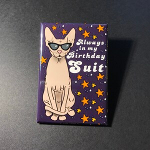 Puede incluir: Un im&aacute;n morado con una imagen de dibujos animados de un gato sin pelo con gafas de sol. El gato est&aacute; sentado con las piernas cruzadas. El fondo es un cielo estrellado morado con estrellas naranjas. El texto en el im&aacute;n dice "Always in my Birthday Suit."