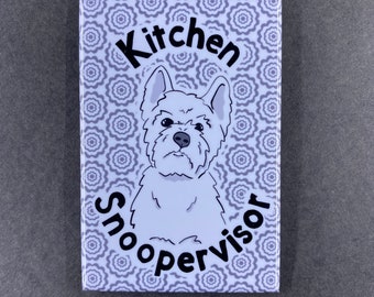 Puede incluir: Un imán de cerámica blanco con un patrón floral morado. El imán presenta un perro blanco de dibujos animados con el texto "Kitchen Snoopervisor" en negro.