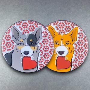 May include: Two round coasters with a heart pattern background. Each coaster features a cartoon dog with a heart in its mouth. One dog is gray and black, the other is orange.