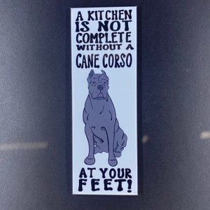 May include: A white rectangular magnet with black text that reads "A kitchen is not complete without a Cane Corso at your feet!" and a black and white illustration of a Cane Corso dog.
