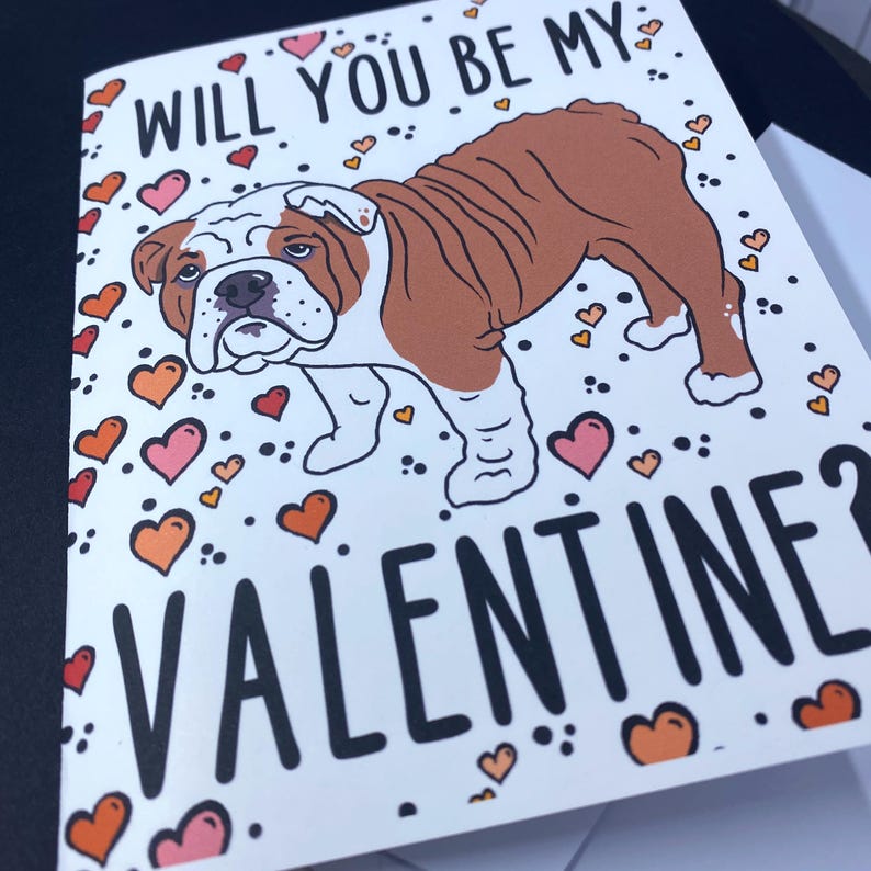 May include: A Valentine's Day card featuring a cartoon bulldog with the text "Will you be my Valentine?" surrounded by pink, orange, and yellow hearts.