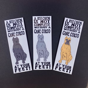 May include: Three white bookmarks with black text and illustrations of Cane Corso dogs. The text reads "A kitchen is not complete without a Cane Corso at your feet!"