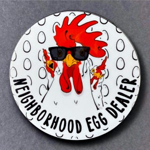 May include: A white chicken with a red comb and wattle wearing sunglasses and a black and white egg pattern background. The text "Neighborhood Egg Dealer" is written around the chicken.