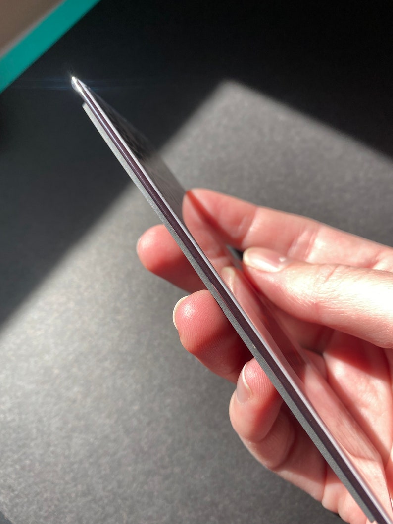 May include: A close-up of a silver phone case with a slightly textured surface. The case is held in a hand, showcasing its slim profile.