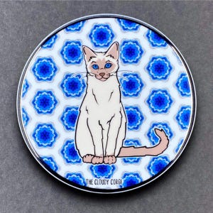 May include: A white Siamese cat with blue eyes sits on a white background with a blue and white floral pattern. The cat is looking directly at the viewer. The text "THE CLOUDY CORGI" is at the bottom of the image.