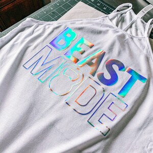 May include: White tank top with a holographic iridescent design that reads "BEAST MODE".