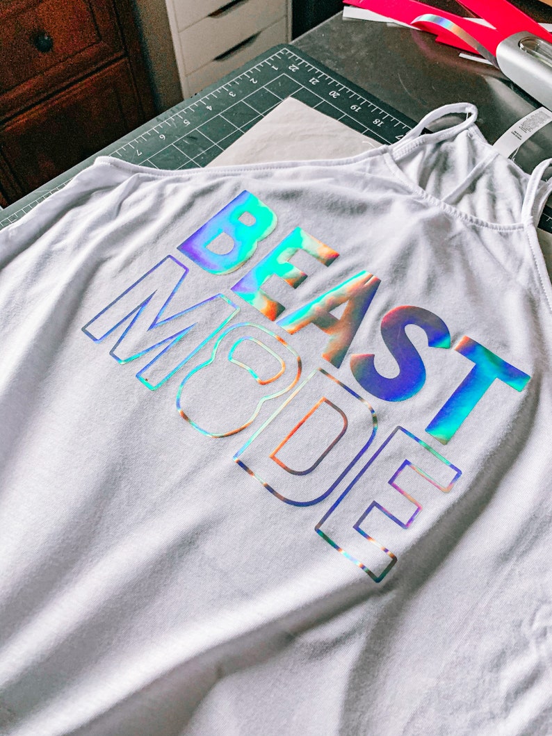 May include: White tank top with a holographic iridescent design that reads "BEAST MODE".