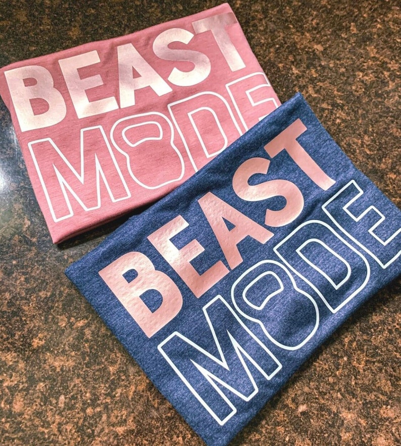 May include: Two t-shirts with the text "BEAST MODE" in rose gold lettering. The shirts are in different colours, one is pink and the other is blue.