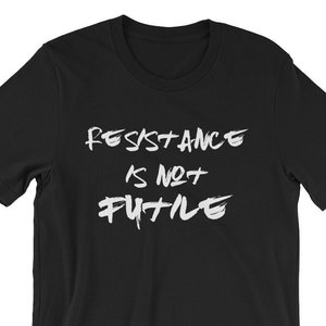 May include: Black t-shirt with white text that reads "Resistance is not futile" in a bold, brushstroke font.
