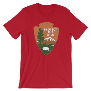 May include: Red t-shirt with a green, brown, and white graphic of a national park arrowhead with the text "PROTECT THE WILD".