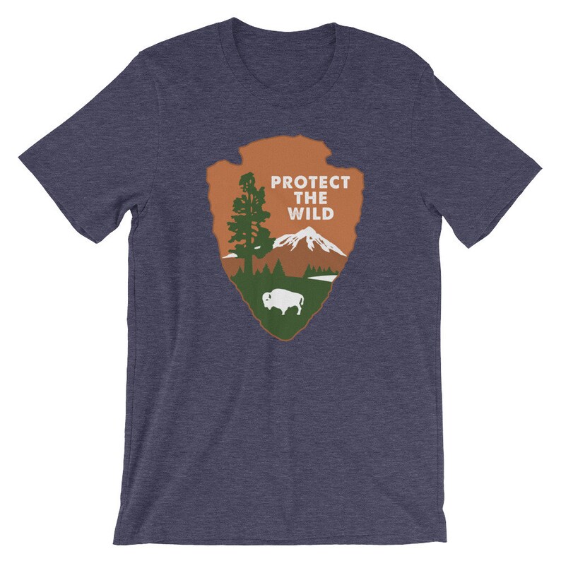 May include: A navy blue t-shirt with a brown and green graphic of a mountain, a tree, and a buffalo. The graphic is in the shape of a National Park Service arrowhead and says "Protect the Wild".