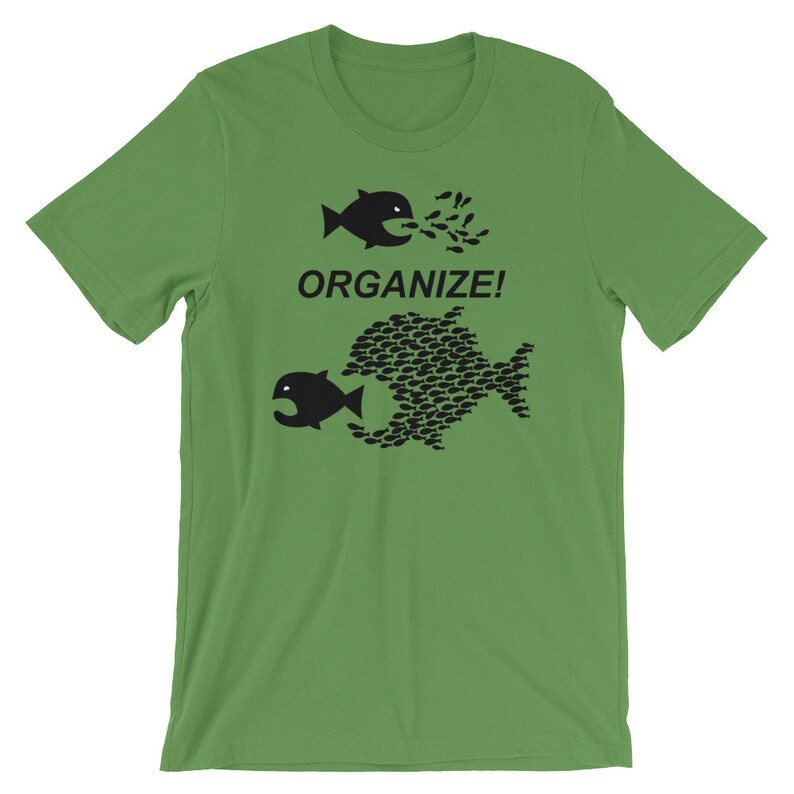 May include: A green t-shirt with a black graphic of two fish. The smaller fish is being swallowed by the larger fish, which is made up of many smaller fish. The text "ORGANIZE!" is printed above the fish.