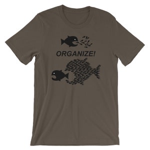 May include: A brown t-shirt with a black graphic of two fish. The smaller fish is eating a large number of smaller fish. The text "ORGANIZE!" is printed below the fish.