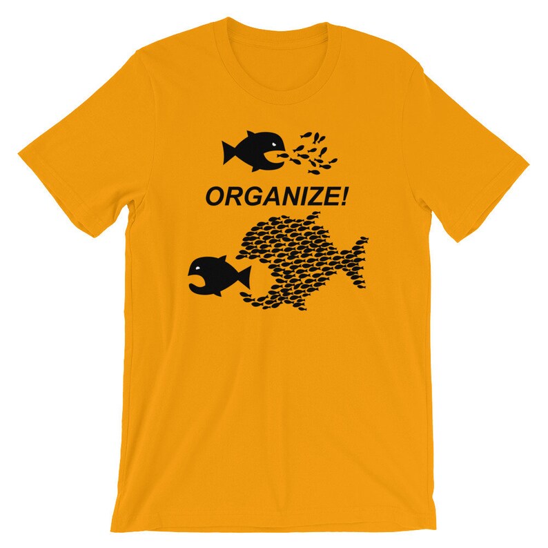 May include: A yellow t-shirt with a black graphic of two fish. The larger fish is made up of many smaller fish. The text "ORGANIZE!" is printed below the fish.