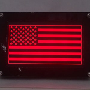 May include: A black framed LED light with a red American flag design.