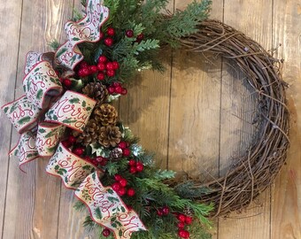 May include: A brown grapevine wreath decorated with green cedar sprigs, red berries, and pine cones. A beige ribbon with the text "Merry Christmas" is tied in a bow.