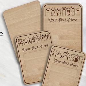 May include: Wooden sticky note holders with engraved cat paw designs. The holders feature a rectangular shape with rounded corners and space for notes. The text "Your Text Here" is displayed on the holders. The image also includes the text "Cuttle Template Example" and "JJ's Maker Studio".