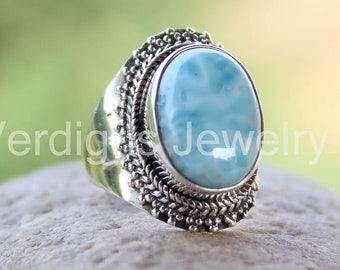 May include: A silver ring with a large oval blue gemstone. The ring has a detailed silver band with a decorative design.