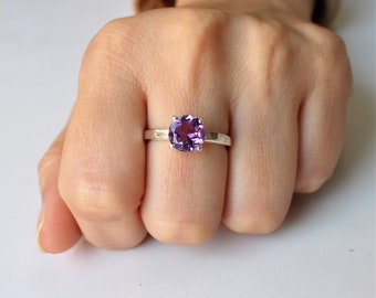 May include: A silver ring with a round, purple amethyst gemstone.
