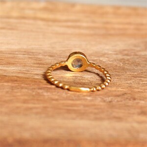 May include: A gold ring with a twisted band and a round, clear gemstone.