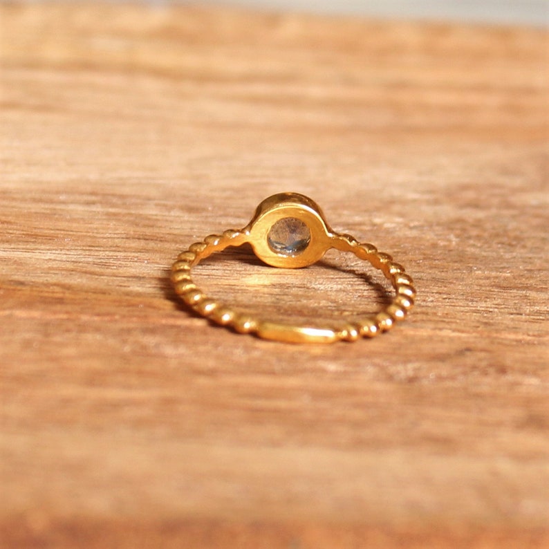 May include: A gold ring with a twisted band and a round, clear gemstone.
