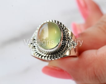 May include: A silver ring with a green and white oval gemstone set in a decorative silver band.
