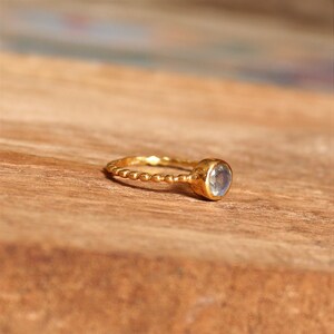 May include: A gold ring with a beaded band and a round, clear gemstone.