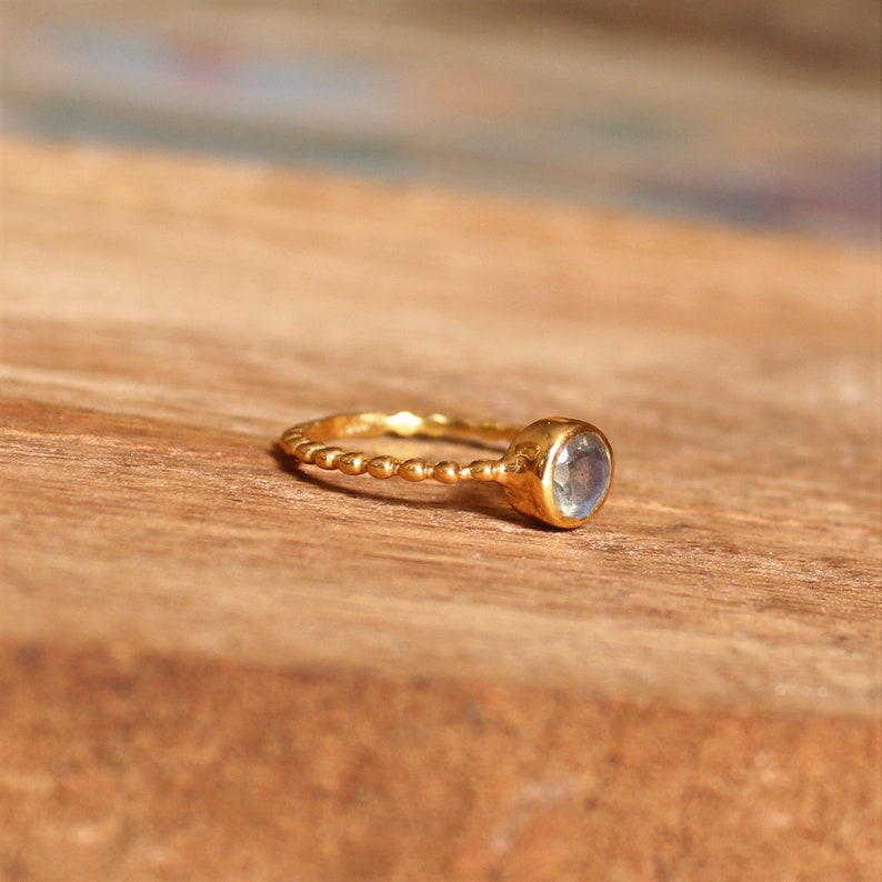 May include: A gold ring with a beaded band and a round, clear gemstone.