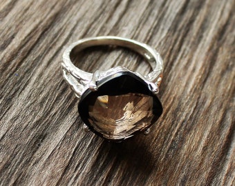 May include: A silver ring with a large, faceted, smoky quartz gemstone. The ring band is textured and has a delicate design.