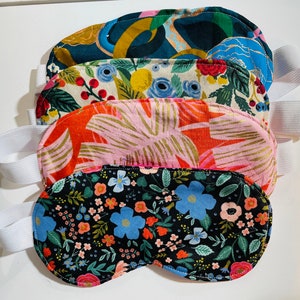 Puede incluir: Cuatro máscaras para dormir de colores con bandas elásticas. Las máscaras presentan diferentes patrones florales y geométricos en tonos de rosa, azul, verde y dorado.